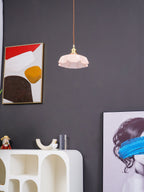 A different angle beside the same abstract print shows this Clérachic pendant's pink pleated glass shade and twisted cord.