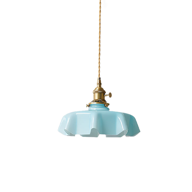 A plain white studio shot shows this Clérachic pendant's blue pleated glass shade and brass fitter up close.