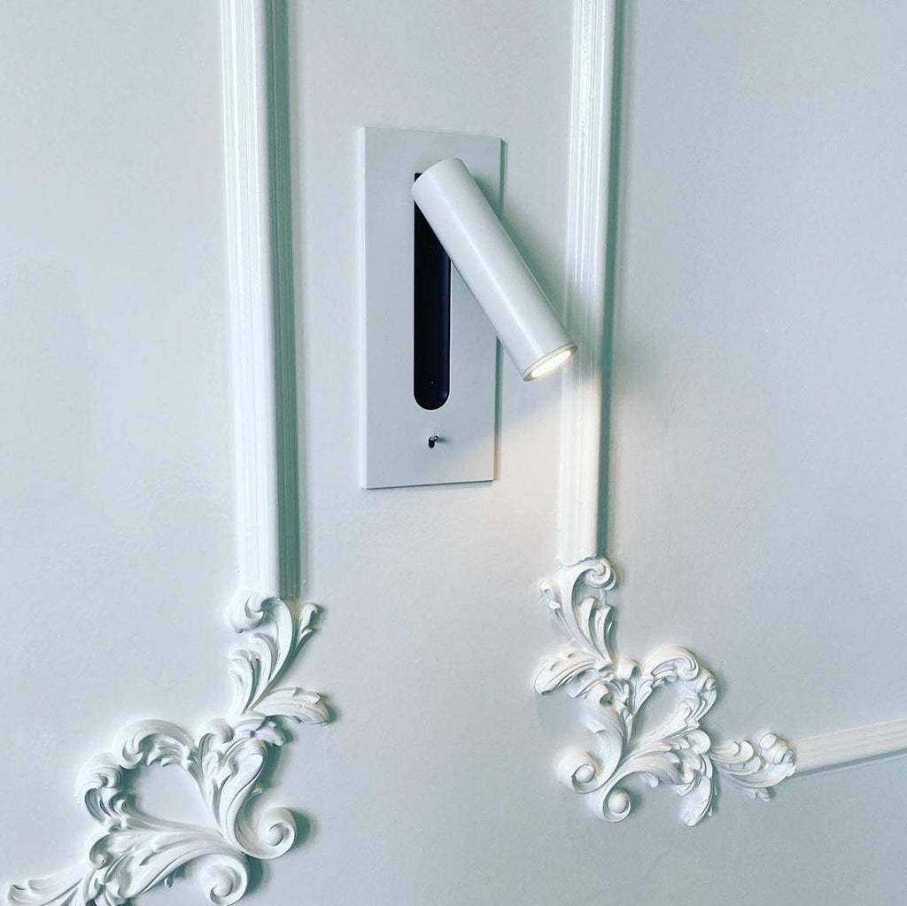 Mounted beside ornate white moulding, this Clérachic reading light in matt white sits unlit on a pale wall.