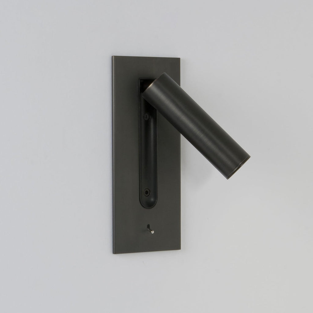 This Clérachic reading light in bronze, unlit, head swung out to the side, on a plain grey background.