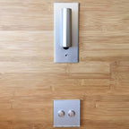 This Clérachic reading light in nickel is mounted above a light switch panel on a bamboo wood wall.