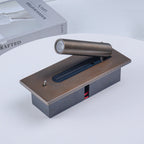 Close view of this Clérachic reading light in bronze, shown detached on a wood block prop beside a book.