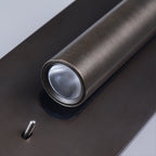 Close view of the lit LED lens on this Clérachic reading light in bronze, angled toward the camera.