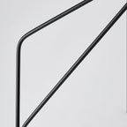 Clérachic black arc floor lamp shown in close-up, the crossed metal support arms visible against a plain background.