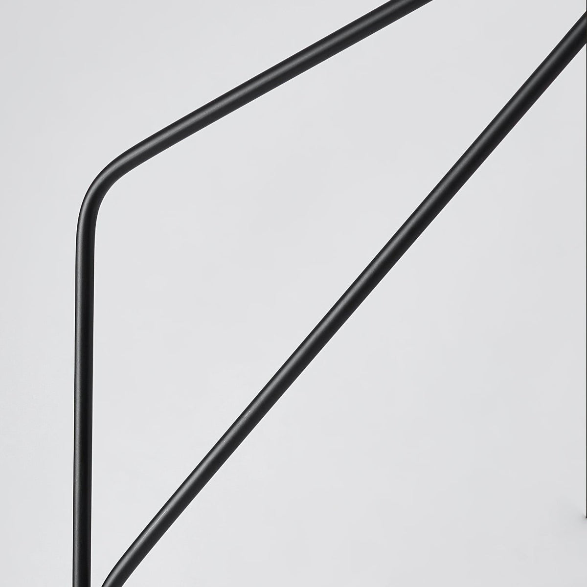 Clérachic black arc floor lamp shown in close-up, the crossed metal support arms visible against a plain background.