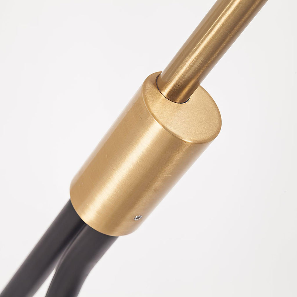 Clérachic black arc floor lamp in close-up, the brass sleeve joint between the black pole and upper arm shown in detail.