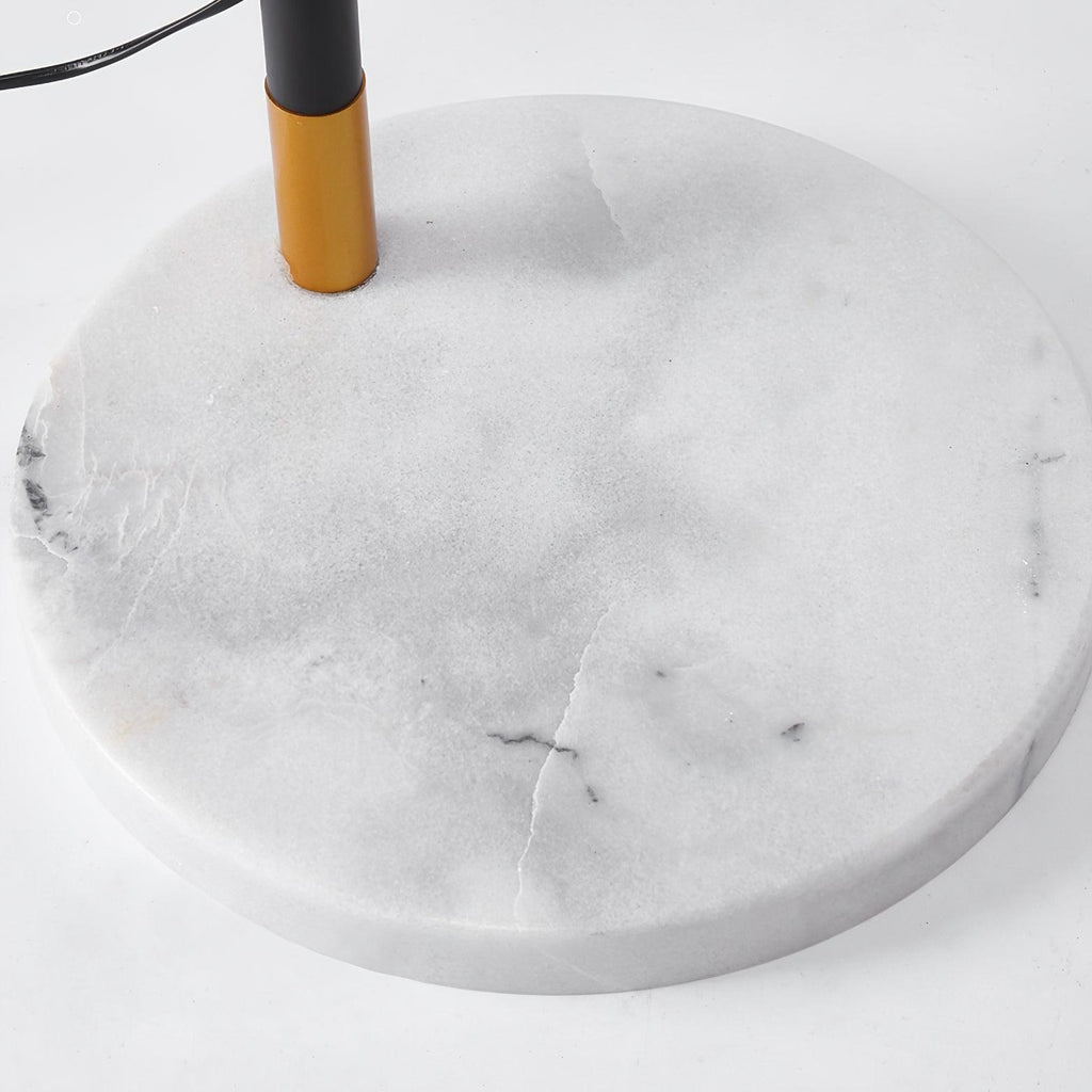 Clérachic black arc floor lamp in close-up, the brass rod meeting its round white marble base shown in detail.