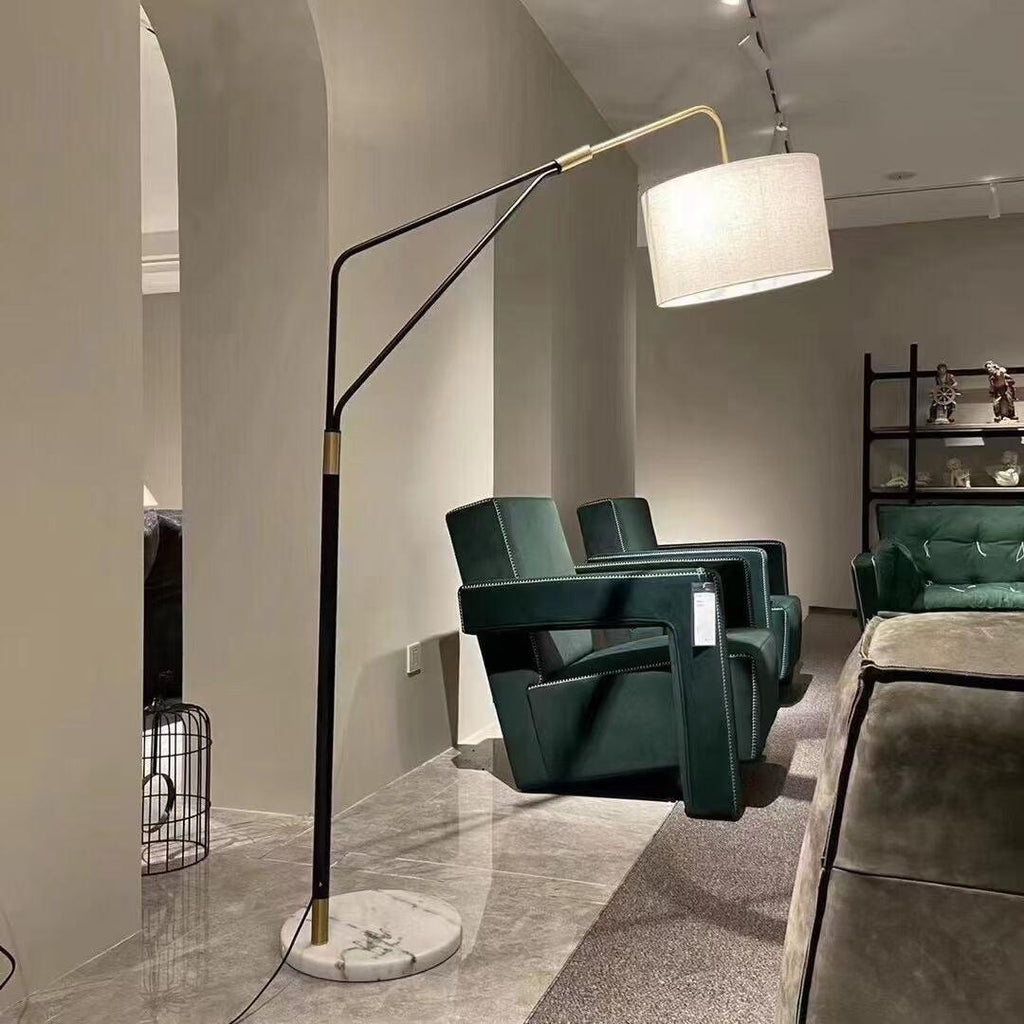 A vaulted interior frames the Clérachic black arc floor lamp, positioned beside dark green velvet chairs and open shelving.
