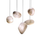 Five alabaster shades in different sculptural forms hung at staggered heights and lit