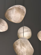 Close cluster of alabaster shades against a grey wall, veining visible in each stone