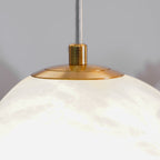 Close-up of the brushed brass canopy cap where the cable meets the alabaster shade