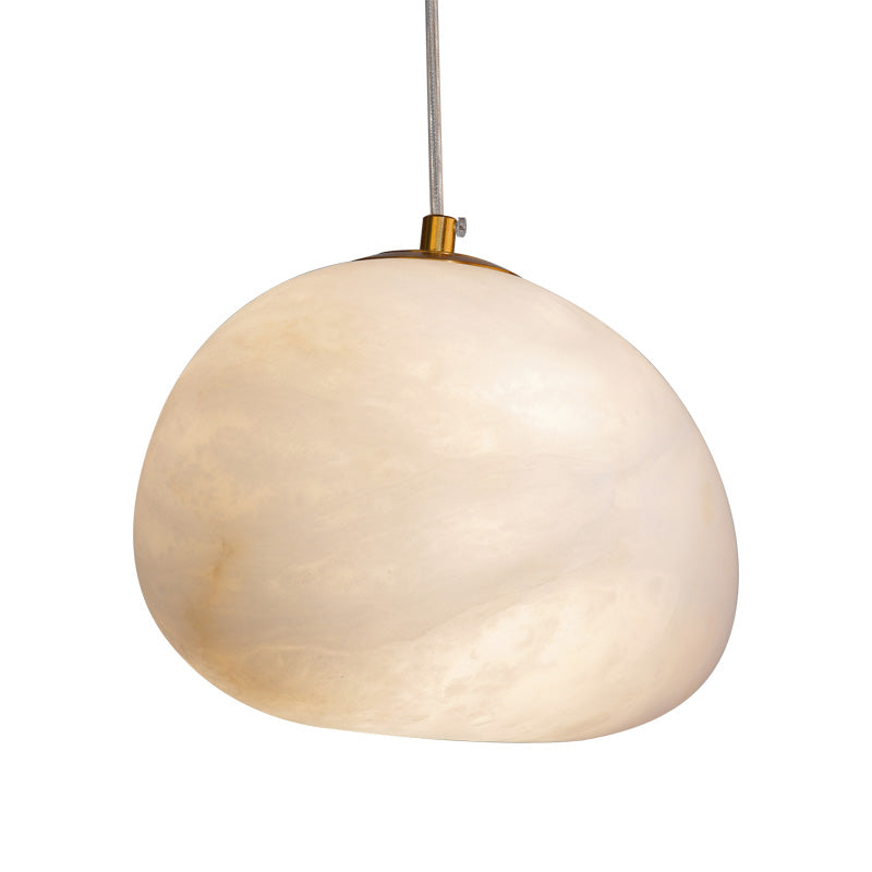 Wide pebble-shaped alabaster pendant shade with a brass cap, hanging unlit on a clear cable