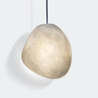 Matte alabaster pebble shade on a black cord, angled to show its irregular hand-shaped form