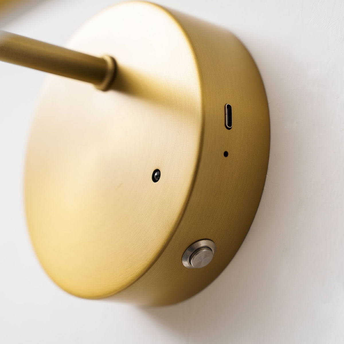Close view of the charging port and power button on the back of this Clérachic wall light's gold-finish canopy.