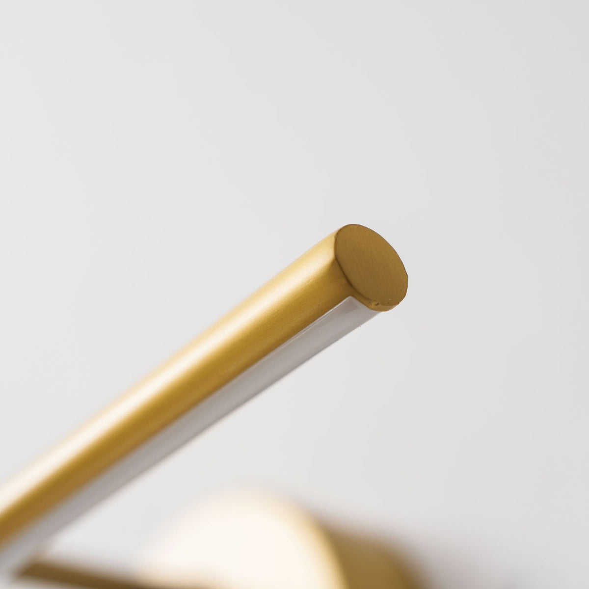 Close view of the angled rod tip on this gold-finish Clérachic wall light.