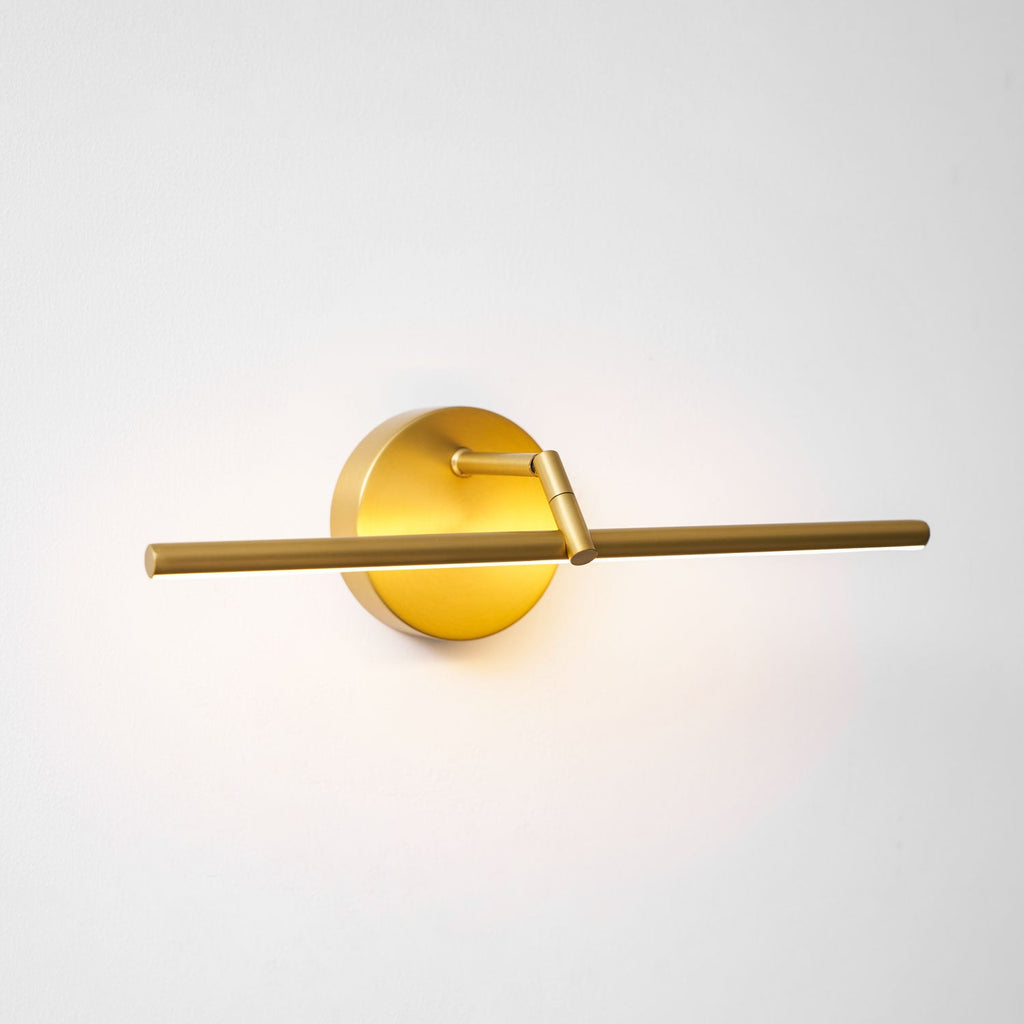 This gold-finish Clérachic wall light glows at an angle, the offset bar casting warm light along the wall.