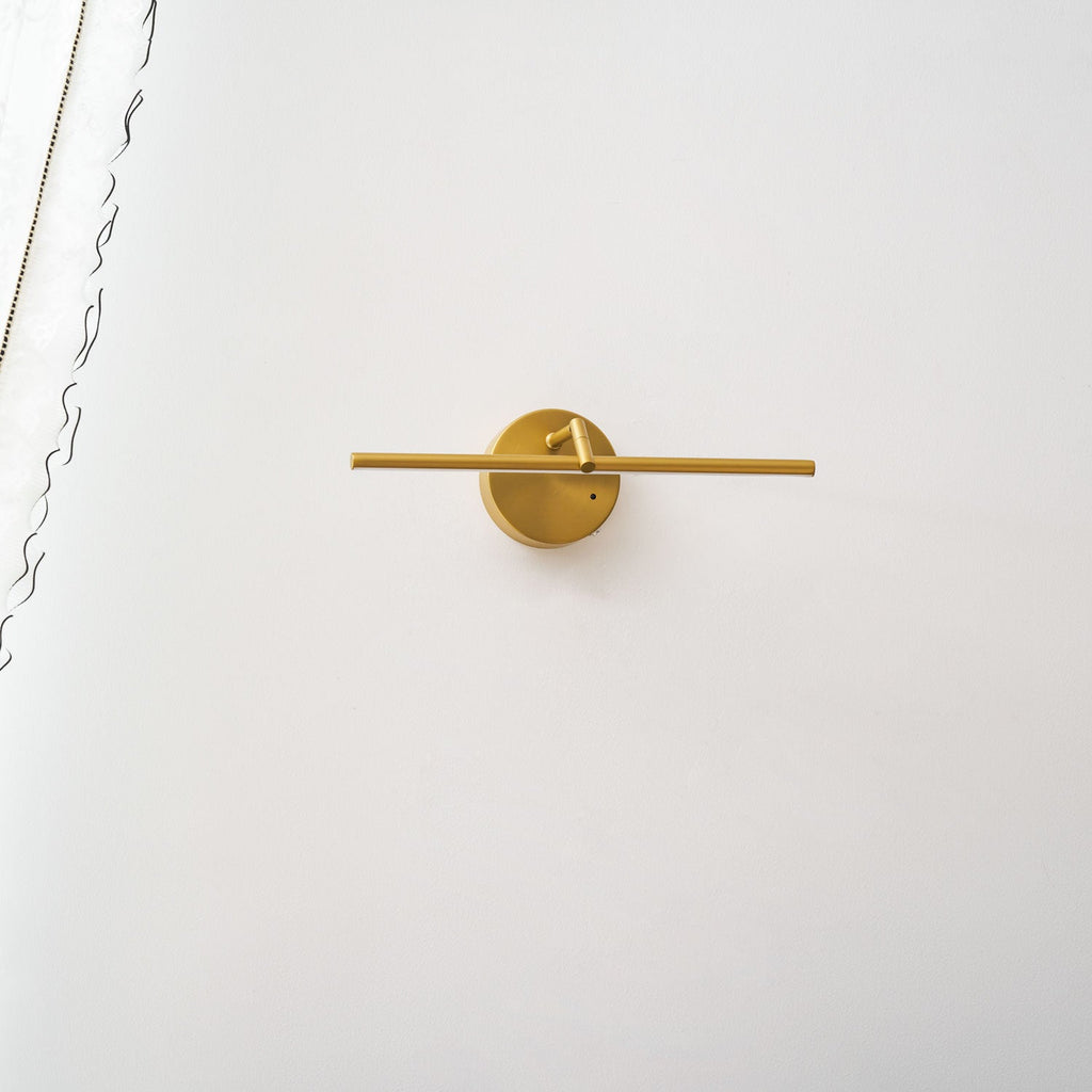 A gold-finish Clérachic wall light shown alone on a plain wall, unlit, angled slightly from the front with no furniture below.