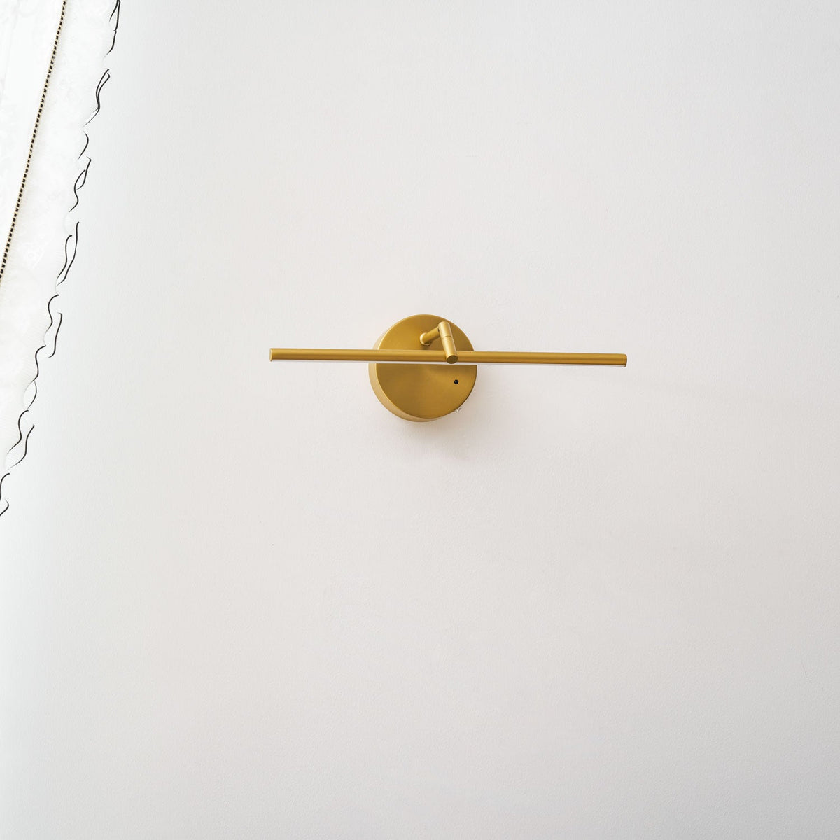 A gold-finish Clérachic wall light shown alone on a plain wall, unlit, angled slightly from the front with no furniture below.