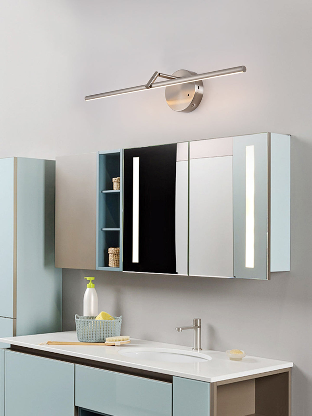 This nickel-finish Clérachic wall light glows above a mirrored bathroom cabinet with open shelving, a sink and a soap dispenser below.