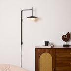 Plug-in swing arm wall lamp with frosted glass shade on wall
