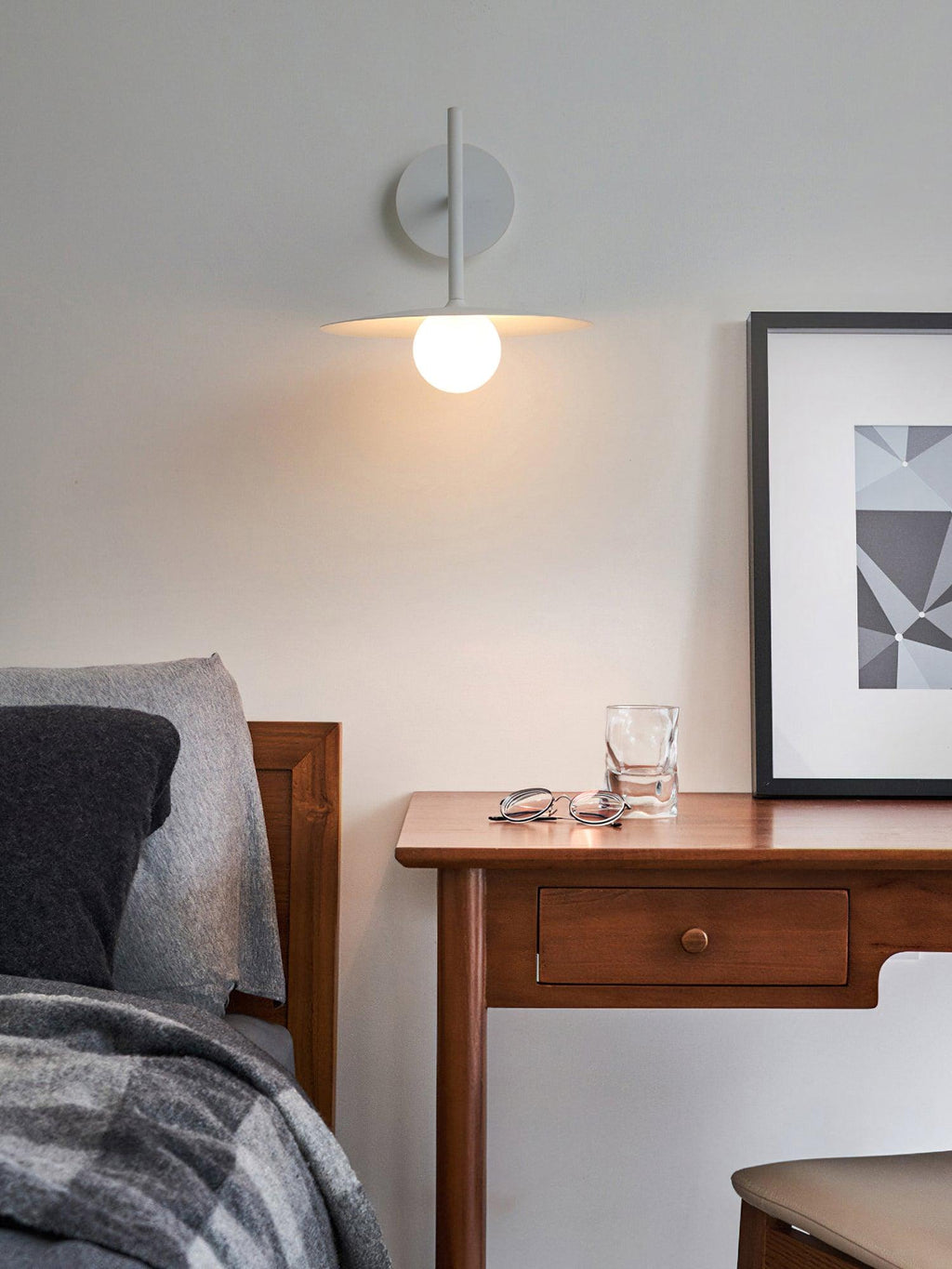 Above a wooden desk, this grey Clérachic wall light glows beneath a framed print.