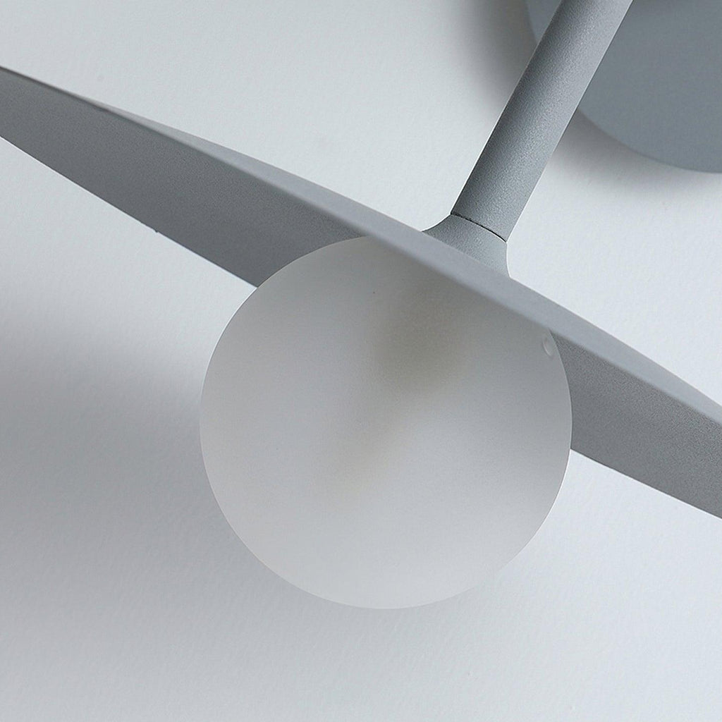 Close view of the glass globe bulb tucked beneath the disc shade of this grey Clérachic wall light.