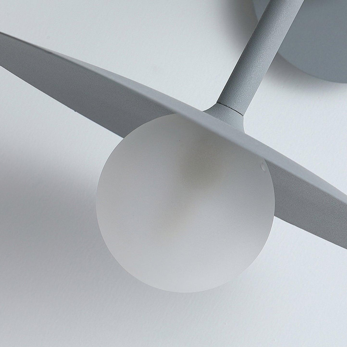 Close view of the glass globe bulb tucked beneath the disc shade of this grey Clérachic wall light.