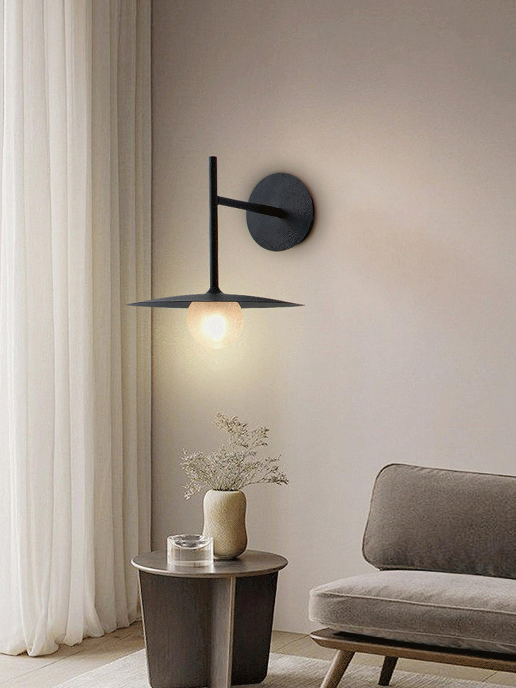Above a side table holding dried flowers, this black Clérachic wall light glows warmly.