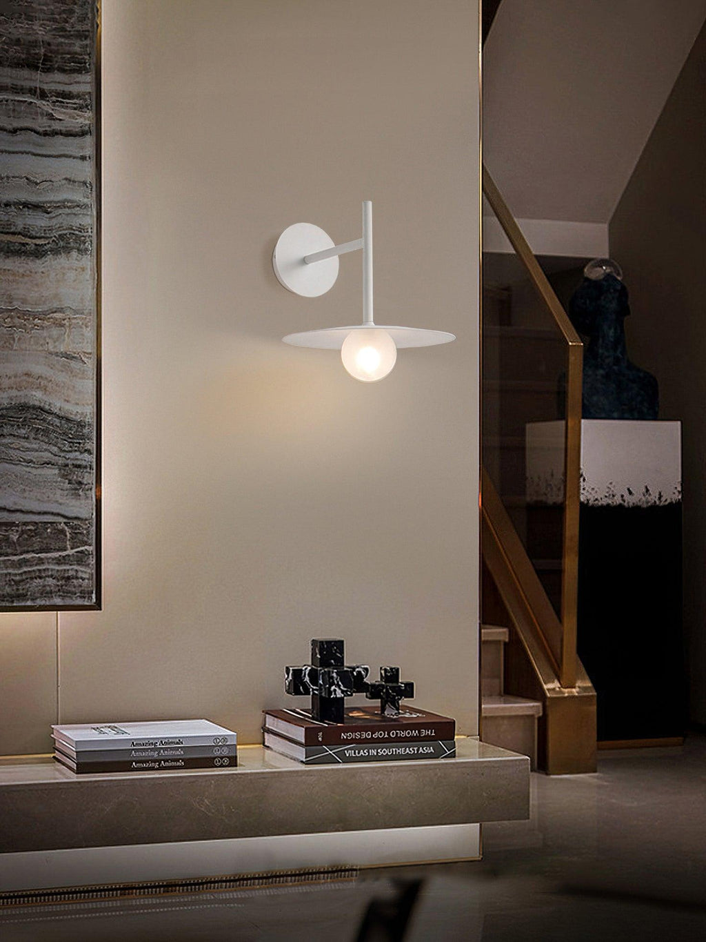 White Clérachic wall light lit above a stone-topped console beside a staircase.