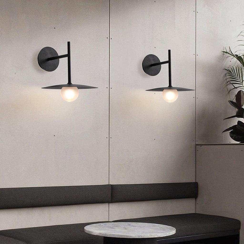 Two black Clérachic wall lights flank a mirrored panel above a marble-topped bench.