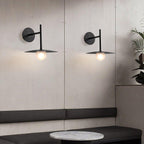 Two black Clérachic wall lights flank a mirrored panel above a marble-topped bench.