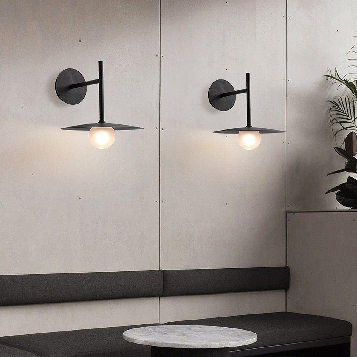 Two black Clérachic wall lights flank a mirrored panel above a marble-topped bench.