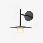 Studio view of this black Clérachic wall light, its glass globe lit beneath a flat disc shade.
