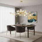 Linear brass ginkgo chandelier lit above a dining room