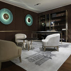 Two mint-toned Clérachic wall lights glow on a dark panelled wall in a lounge with white armchairs and a patterned rug.