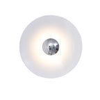 Close view of this white Clérachic wall light glowing warm, its chrome centre bright against the shade.