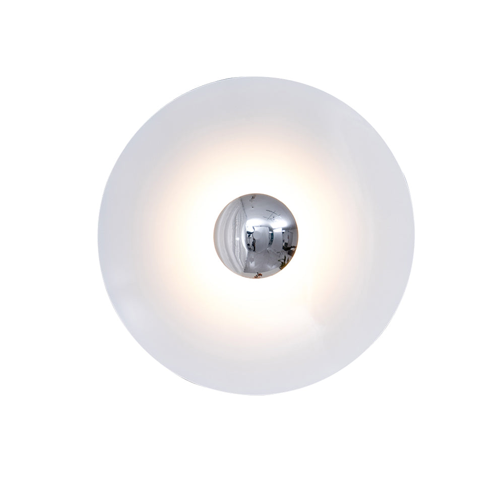 Close view of this white Clérachic wall light glowing warm, its chrome centre bright against the shade.