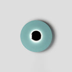 Slightly off-centre in the frame, this pale aqua Clérachic wall light glows softly around a black circular core.