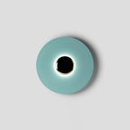 Seen face-on against grey, this pale aqua Clérachic wall light rings its black centre with an even soft light.