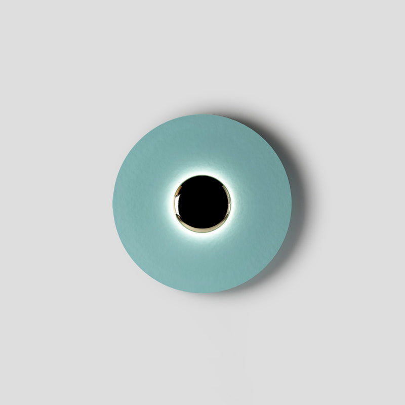 Seen face-on against grey, this pale aqua Clérachic wall light rings its black centre with an even soft light.
