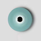 A wider crop reveals more of the pale aqua shade on this Clérachic wall light, its black centre gently lit.