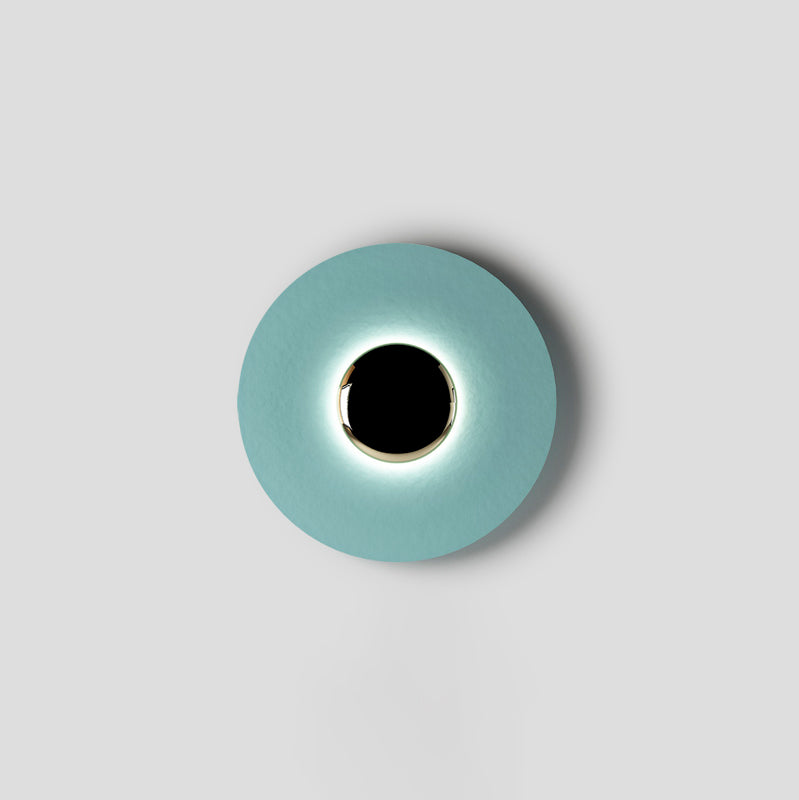 A tighter crop shows the pale aqua Clérachic wall light on grey, light glowing evenly around its black centre.
