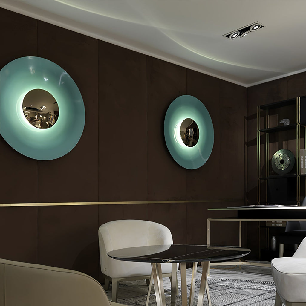 Two Clérachic wall lights, a mint one and a paler aqua one, glow on a dark panelled wall above a dining table.