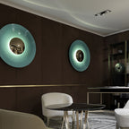 Two Clérachic wall lights, a mint one and a paler aqua one, glow on a dark panelled wall above a dining table.
