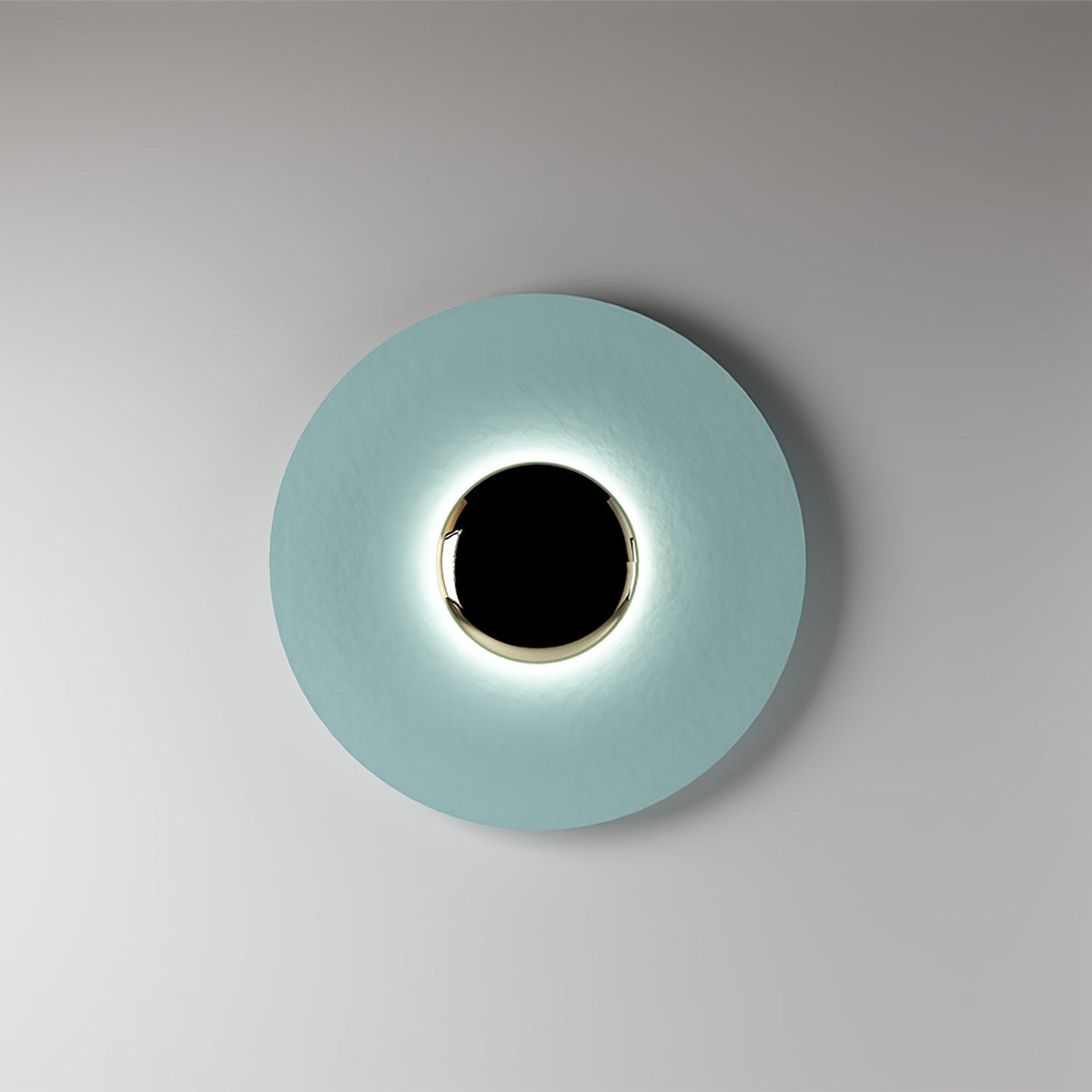 A pale aqua Clérachic wall light on a grey studio backdrop, its black centre softly ringed with light.