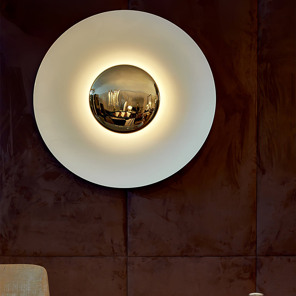This white Clérachic wall light glows on a rust-toned panelled wall, its mirrored centre reflecting the room.