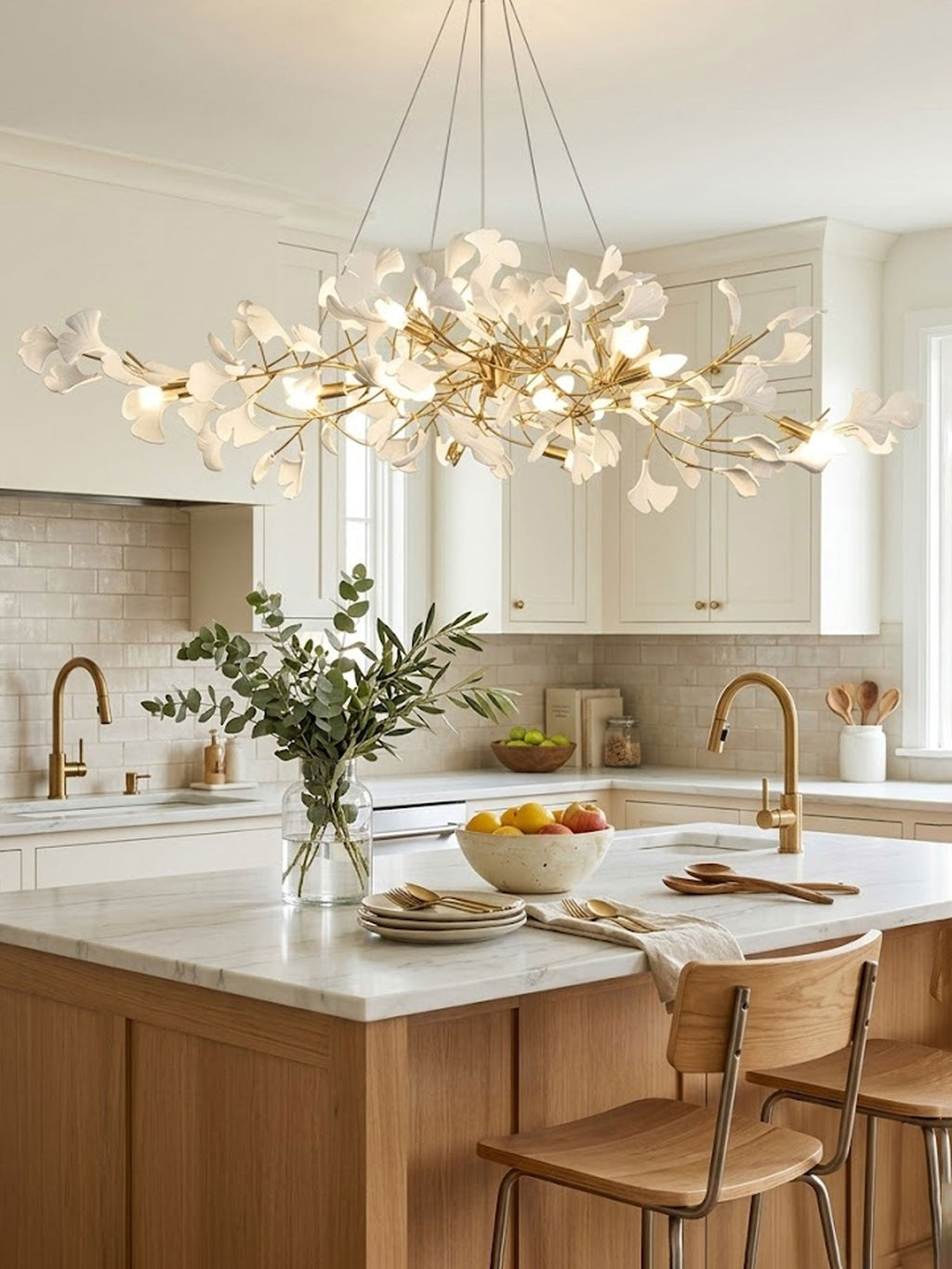 Linear brass ginkgo chandelier glowing over an island