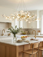 Linear brass ginkgo chandelier glowing over an island