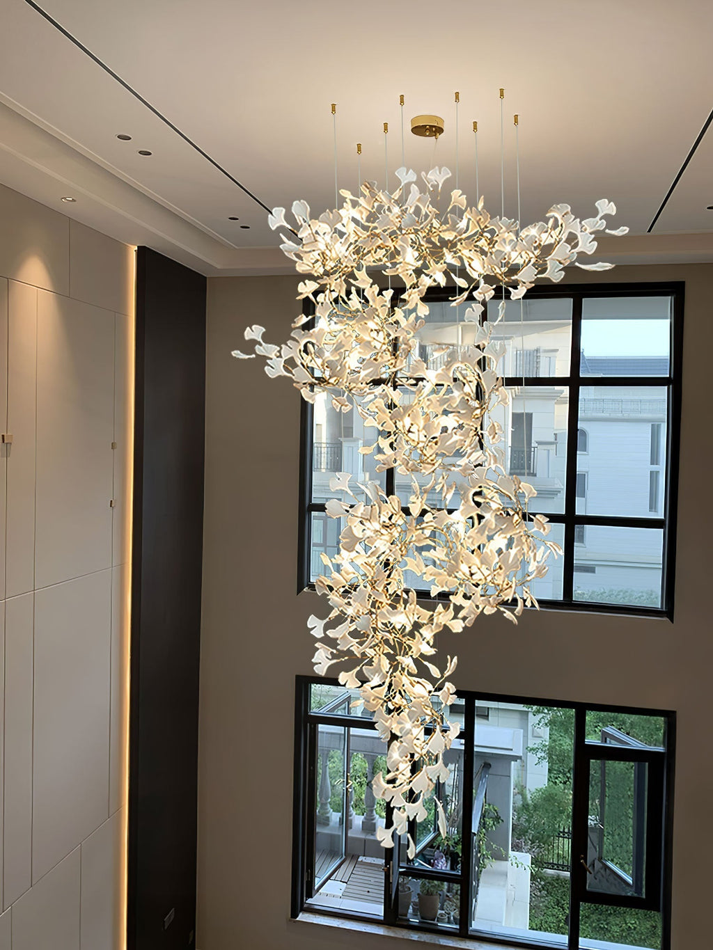 The spiral column lit against a plain wall beside tall black-framed windows spanning two floors.