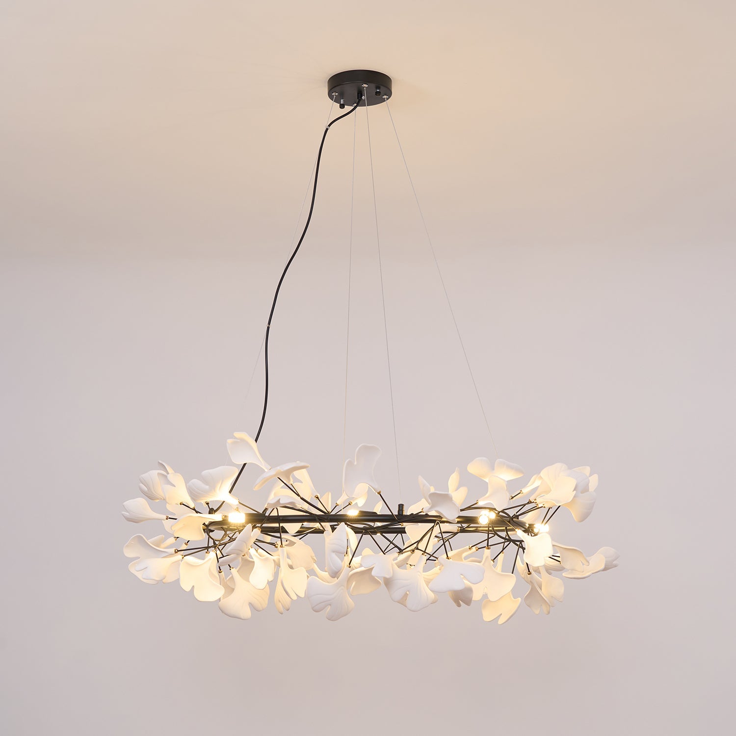 Wide porcelain ginkgo chandelier suspended over a long table